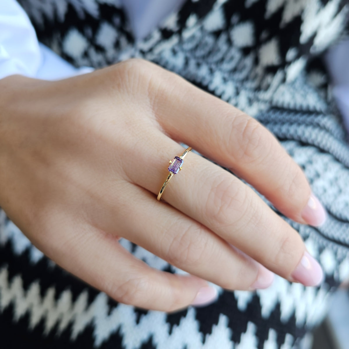 Gold purple-stone baguette solitaire ring worn on hand, side view