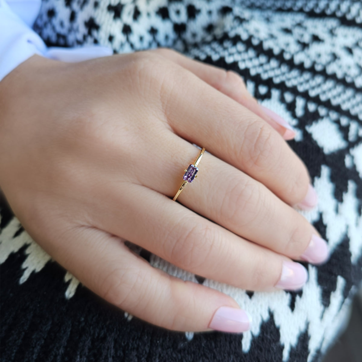 Gold purple-stone baguette solitaire ring worn on hand