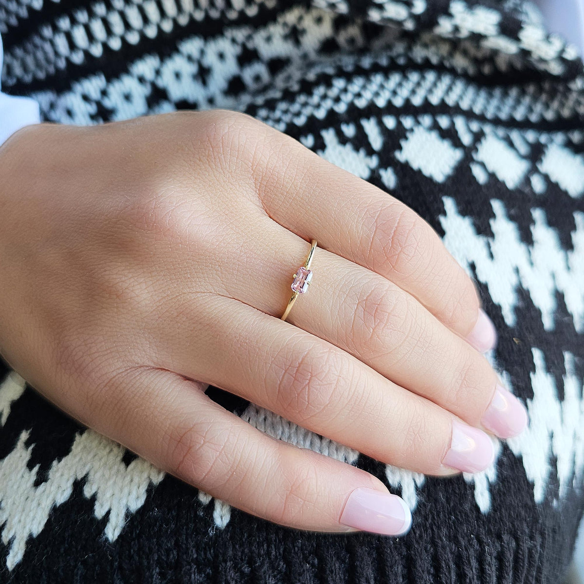 Gold pink-stone baguette solitaire ring worn on hand