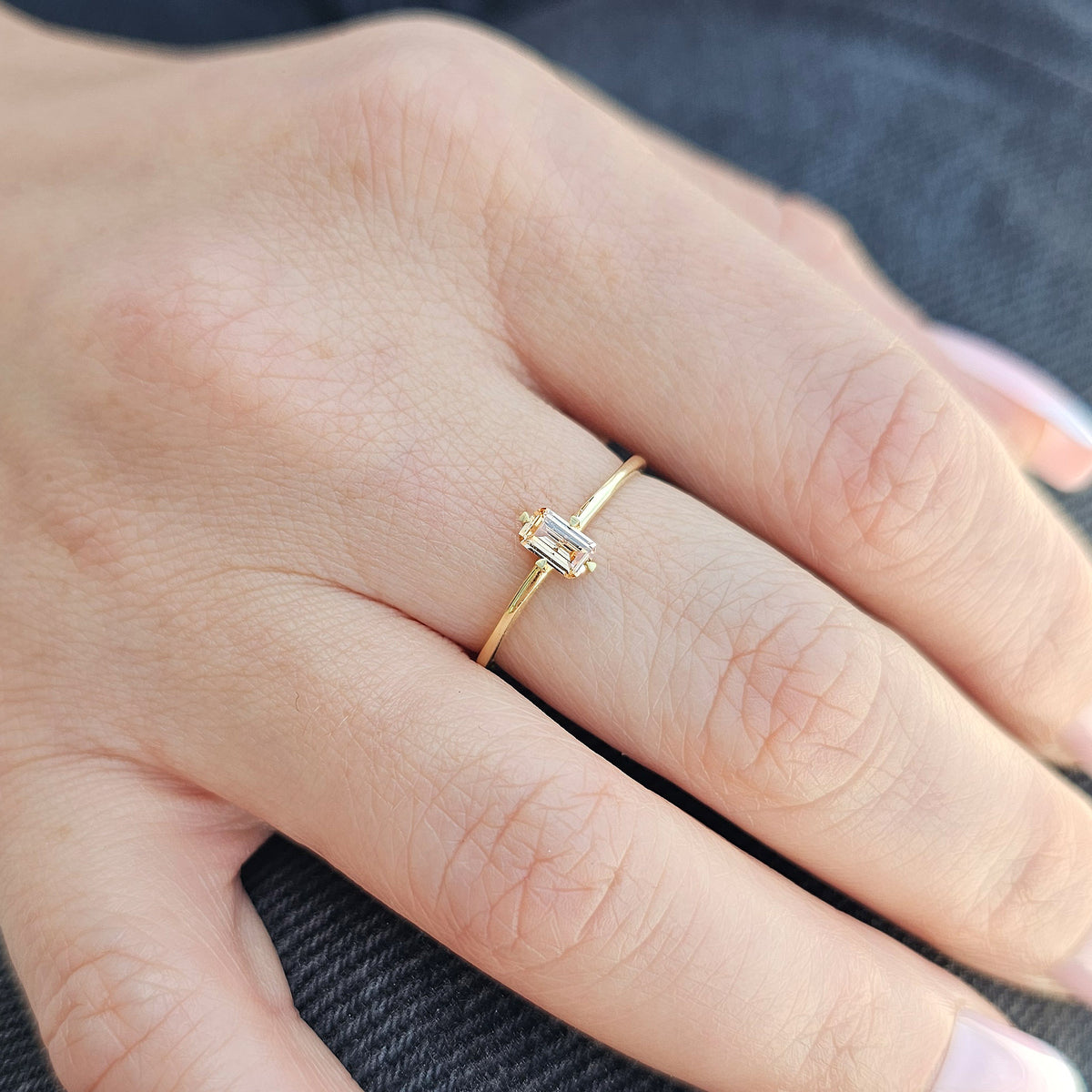 Gold champagne-stone baguette solitaire ring worn on hand, close-up