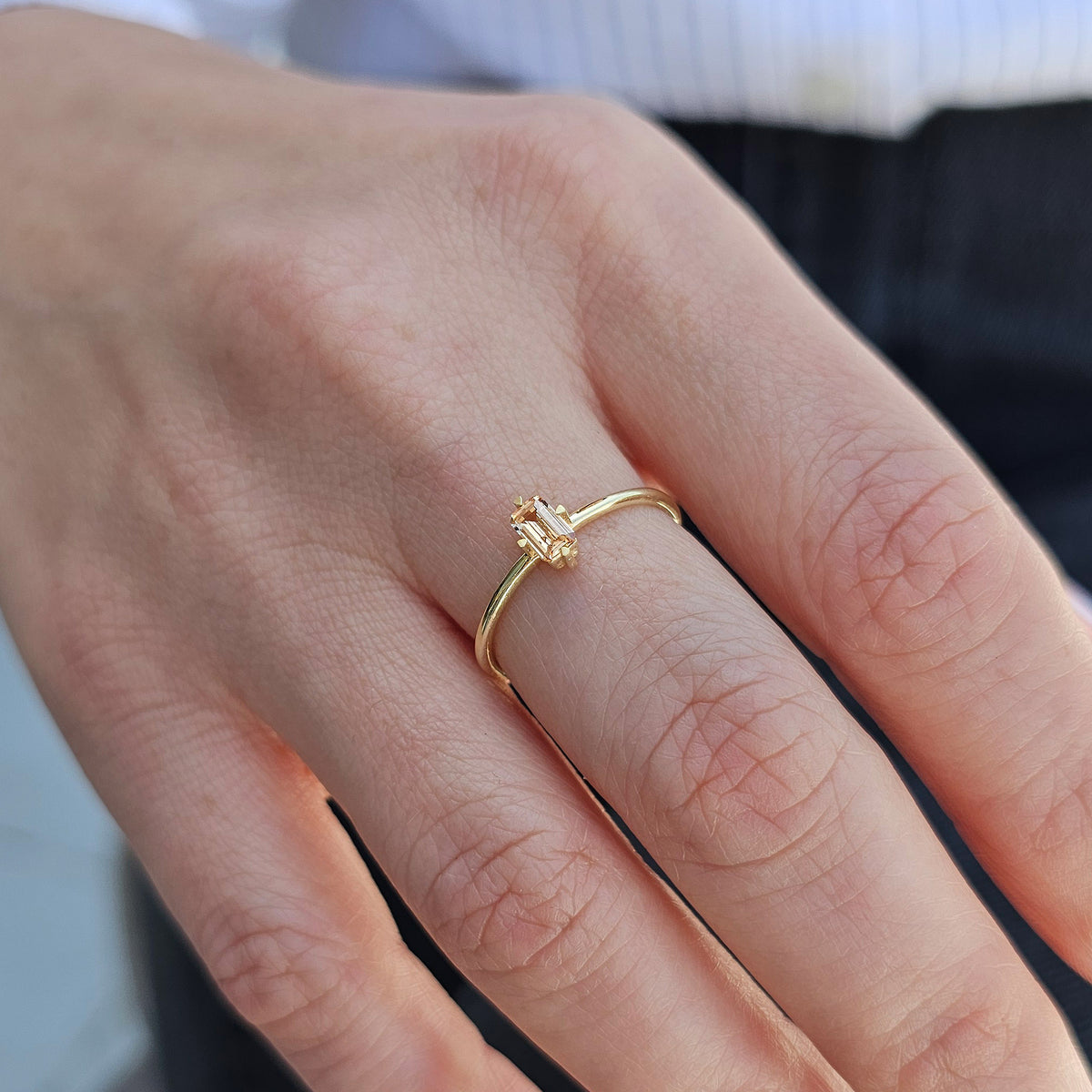 Gold champagne-stone baguette solitaire ring worn on hand, side view