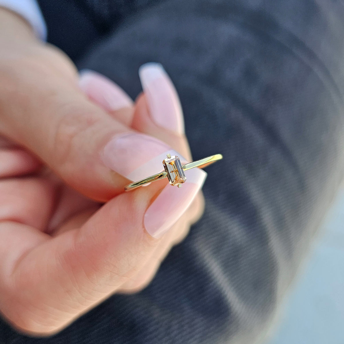 Gold champagne-stone baguette solitaire ring on raised hand