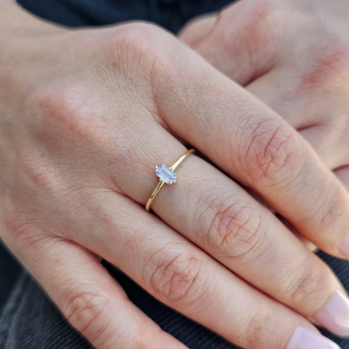 Gold lavender-stone baguette solitaire ring worn on hand