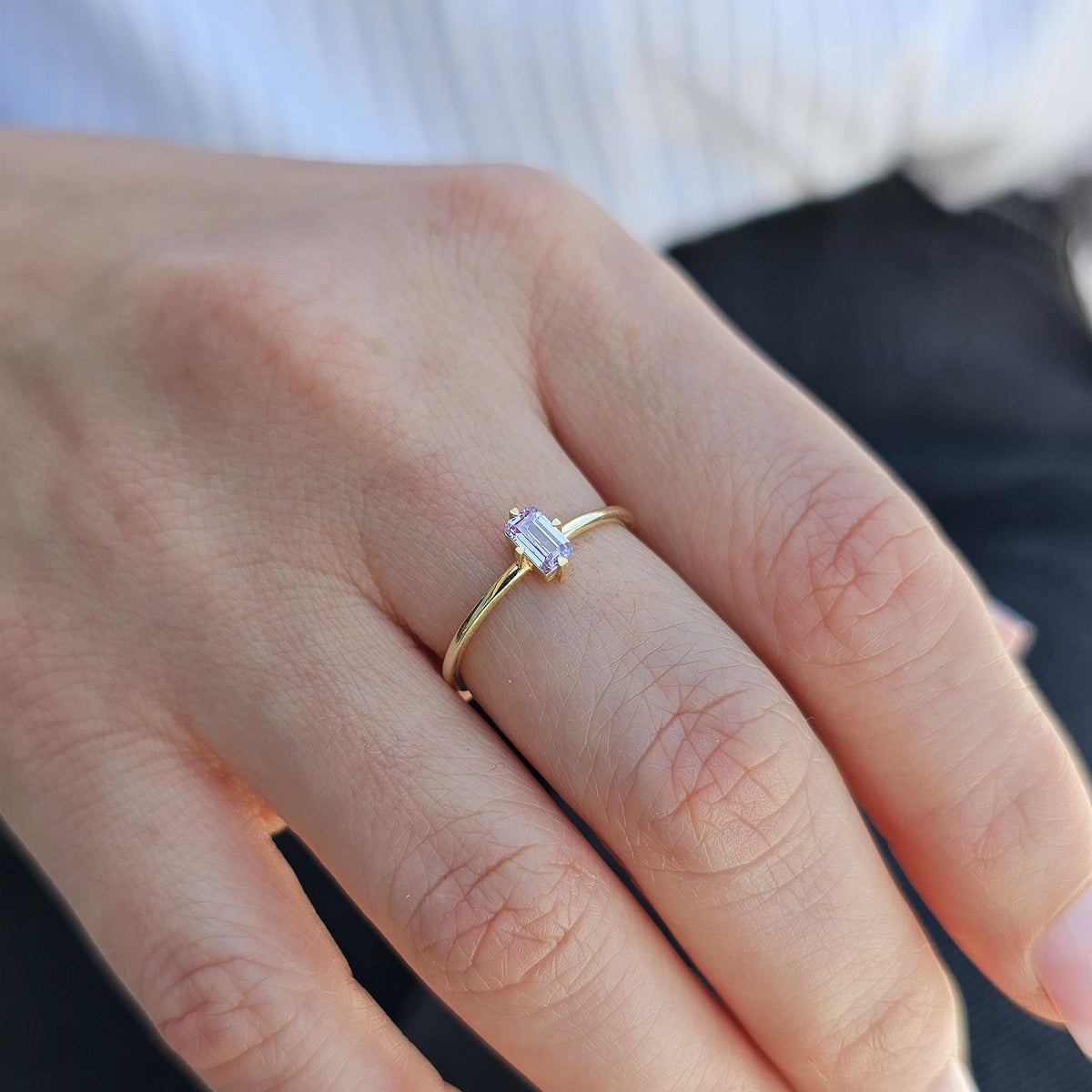 Gold lavender-stone baguette solitaire ring worn on hand, side view