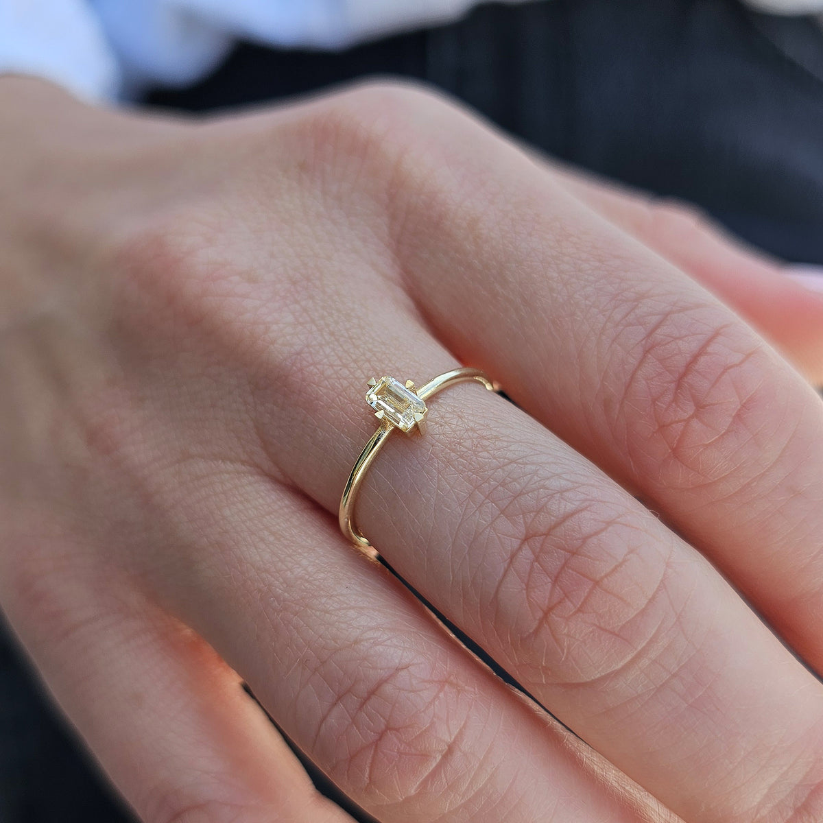 Gold lemon-yellow-stone baguette solitaire ring worn on hand, side view