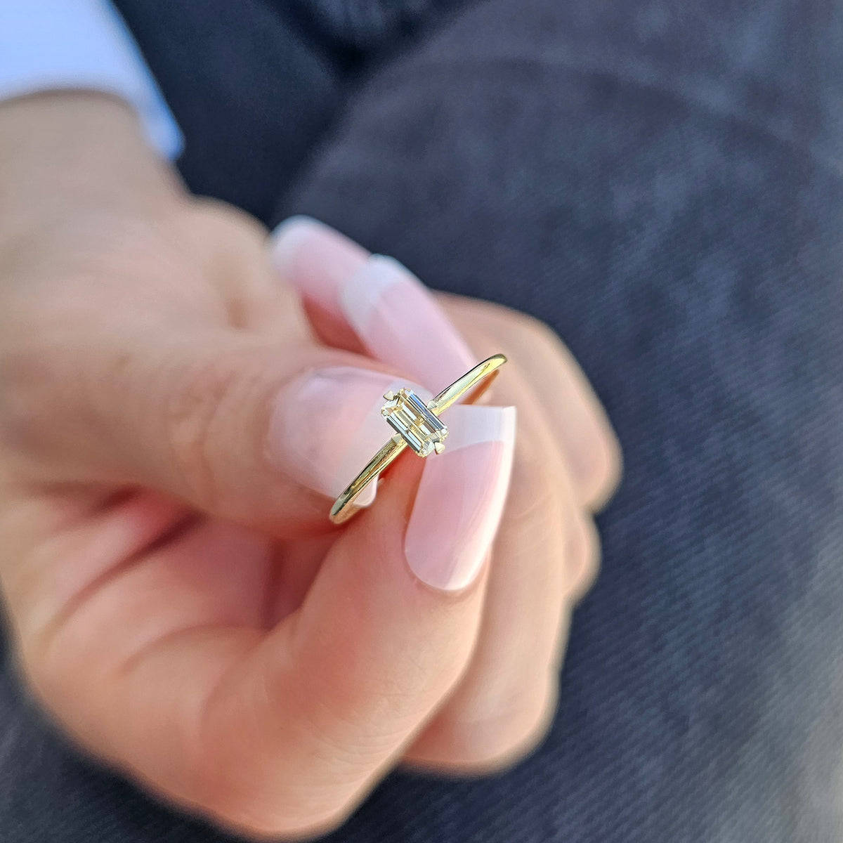 Gold lemon-yellow-stone baguette solitaire ring worn on hand, close-up