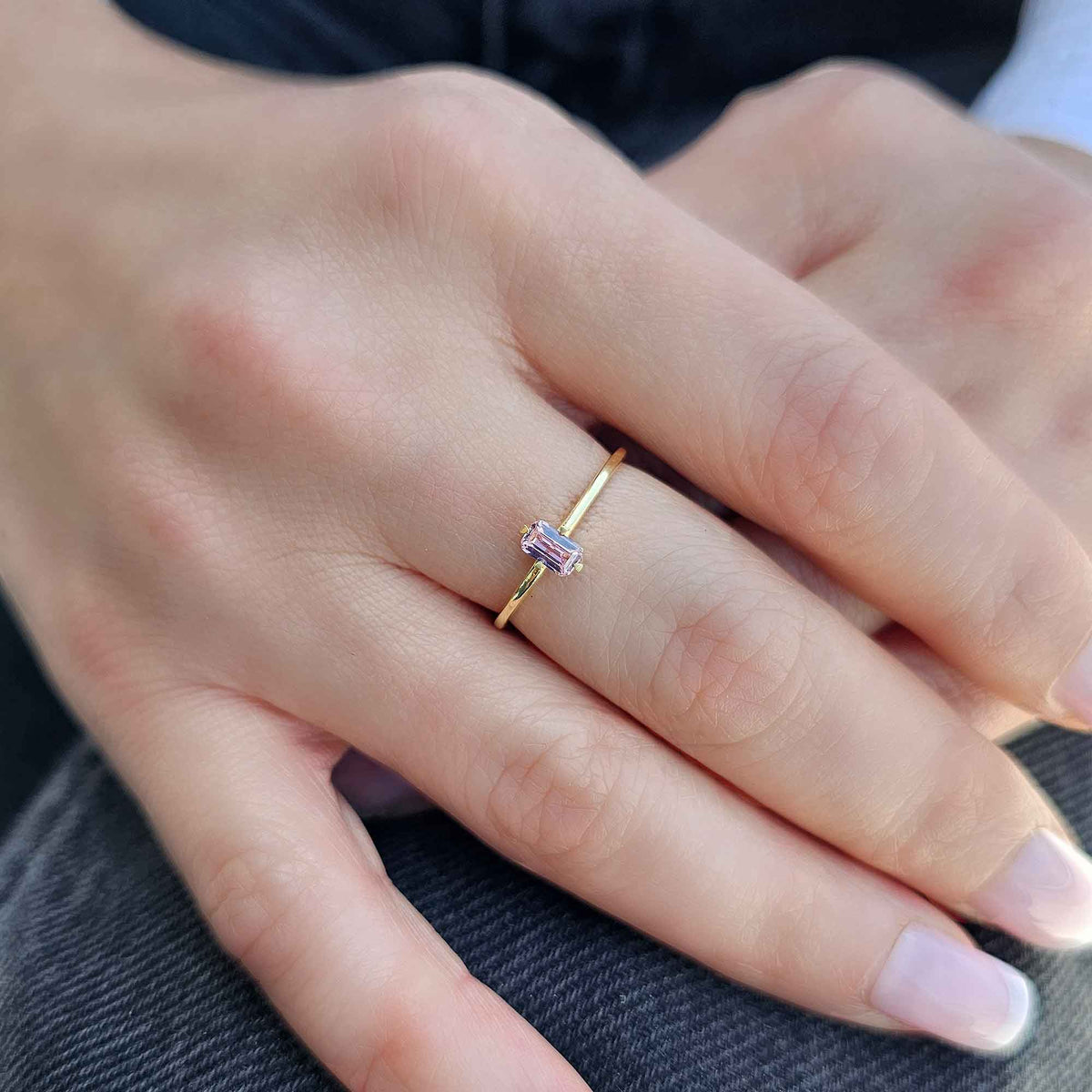 Gold pink-stone baguette solitaire ring worn on hand