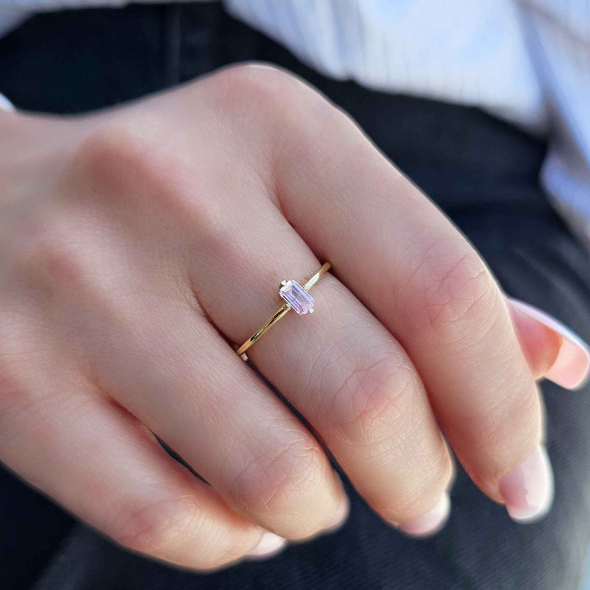 Gold pink-stone baguette solitaire ring on raised hand