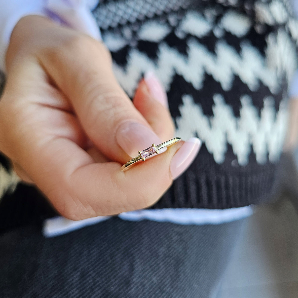 Gold pink-stone baguette solitaire ring worn on hand, side view
