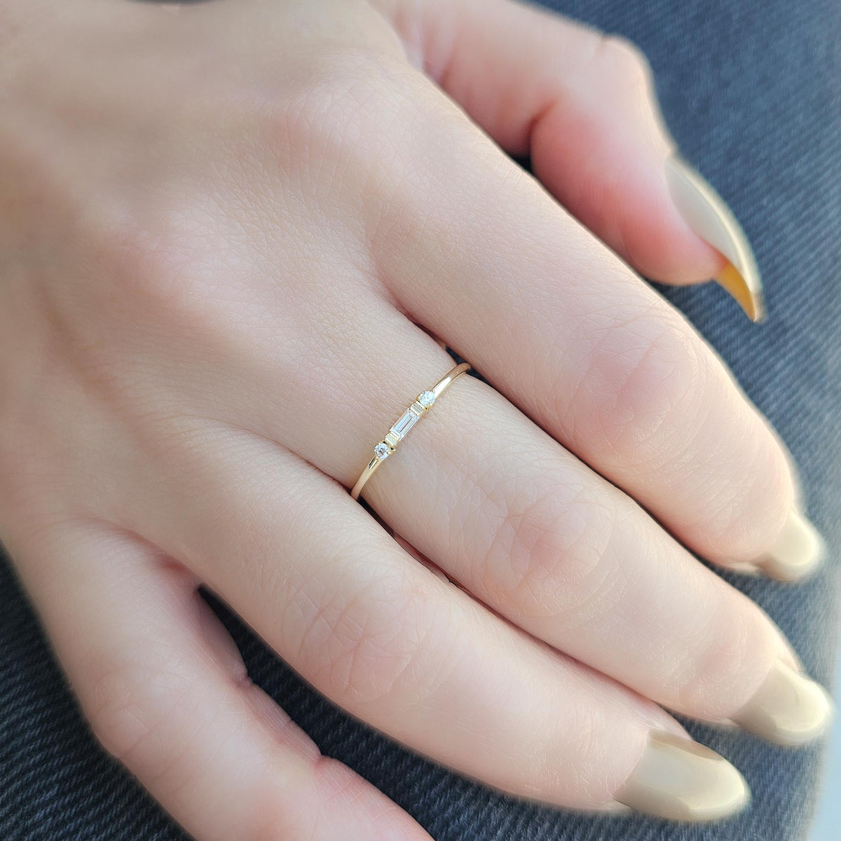 Gold bezel baguette ring on raised hand