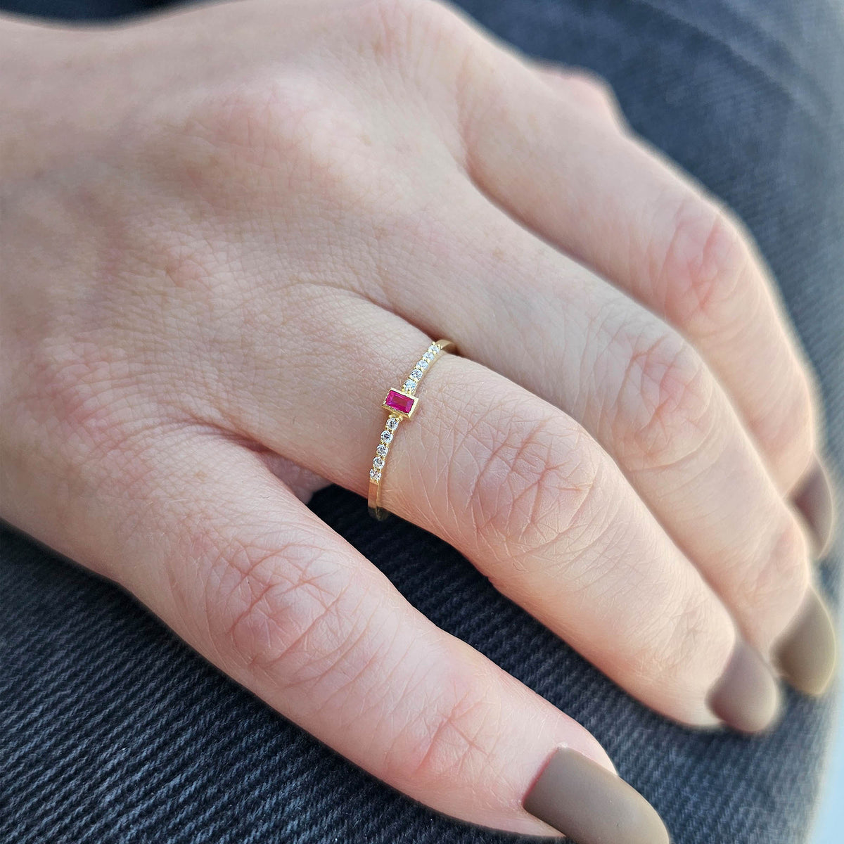 Gold red-stone baguette ring on raised hand