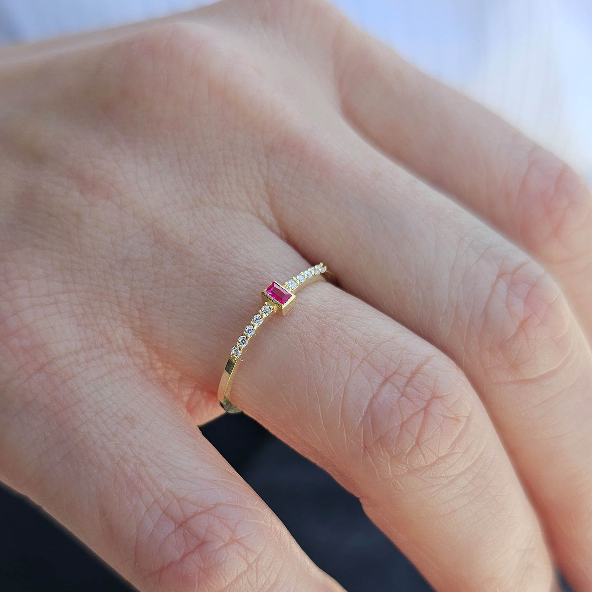 Gold red-stone baguette ring worn on hand, side view