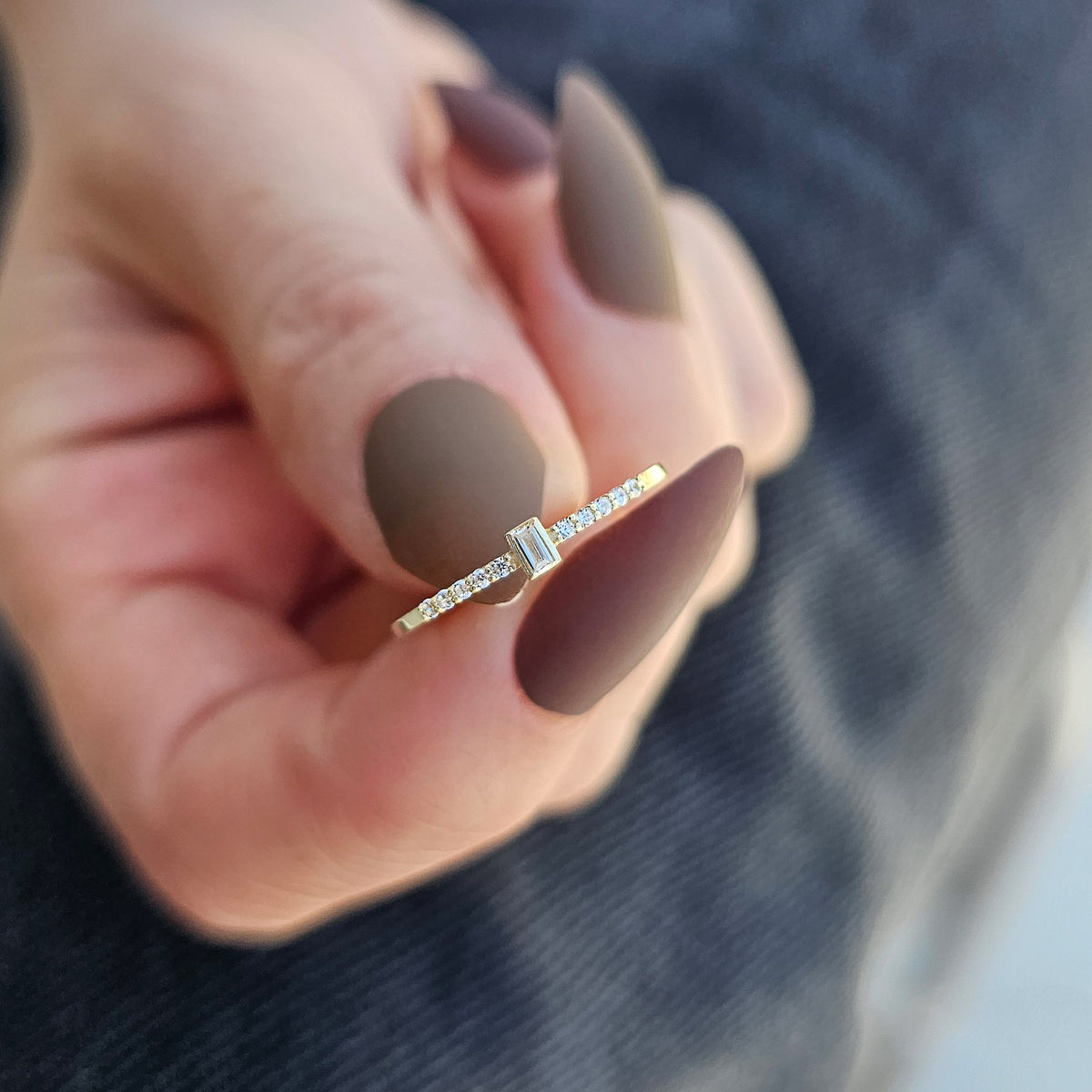 Gold white-stone baguette ring on raised hand