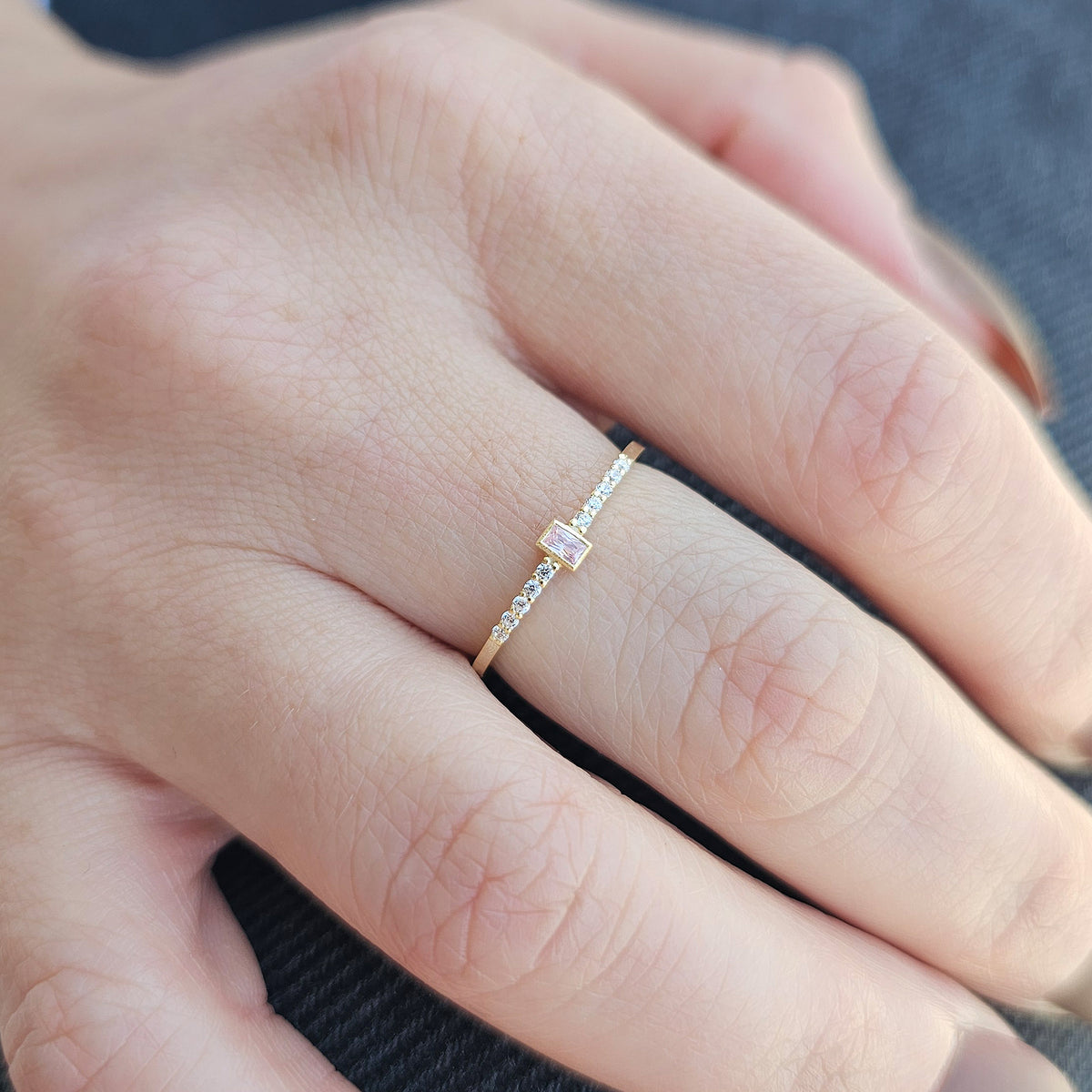 Gold pink-stone baguette ring worn on hand