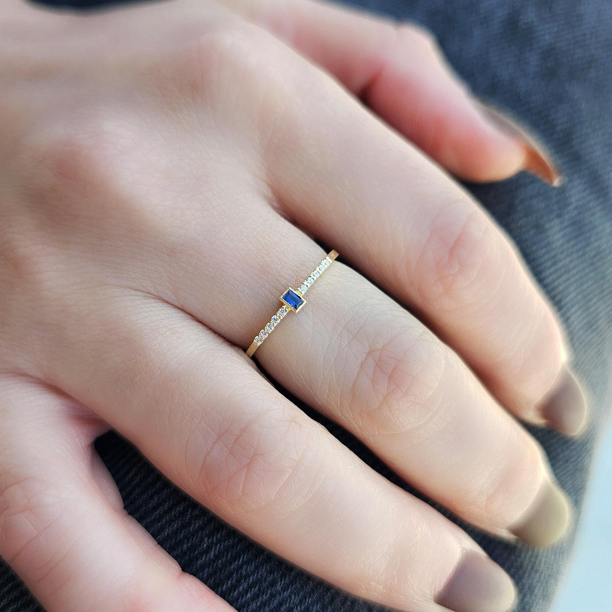 Gold blue-stone baguette ring worn on hand