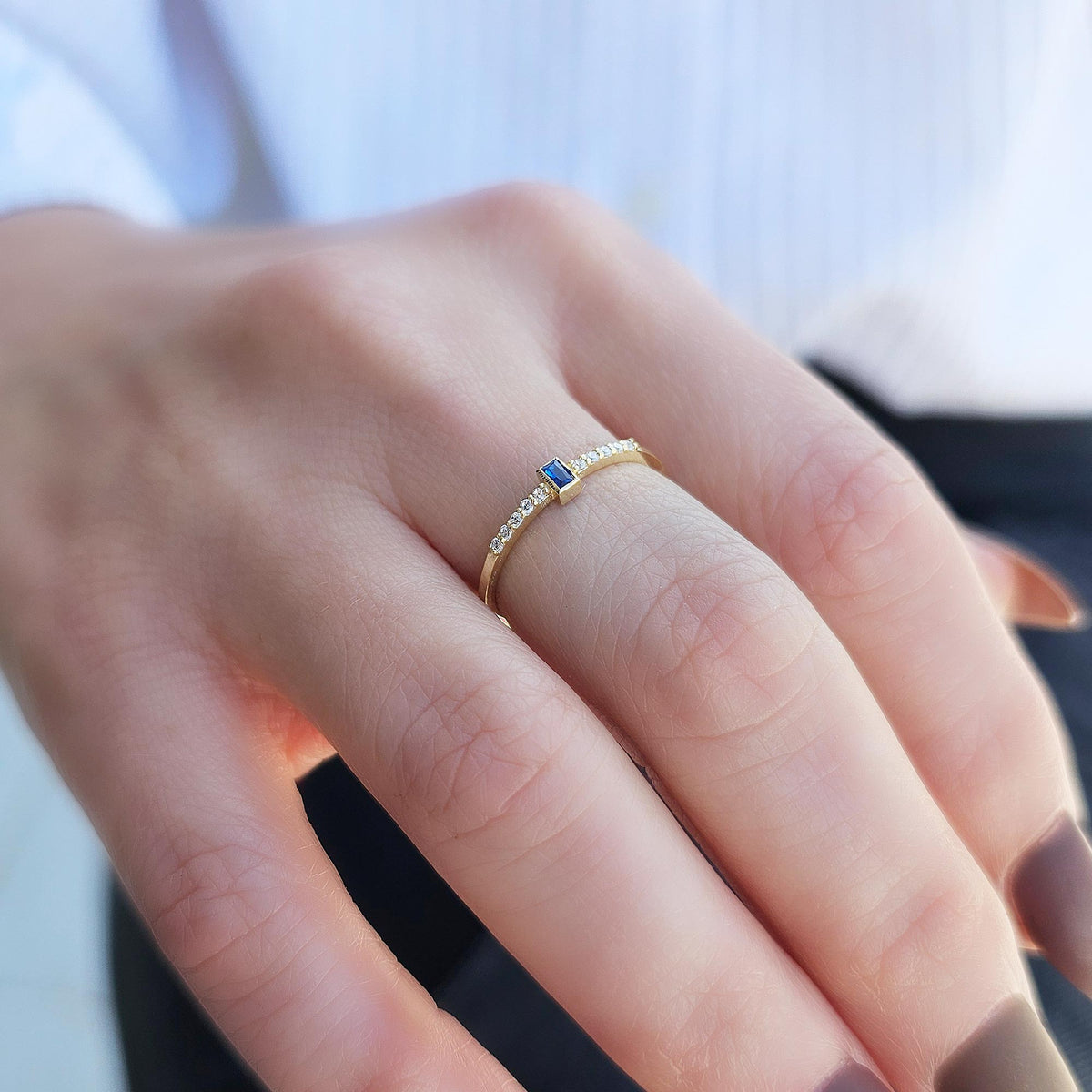 Gold blue-stone baguette ring on raised hand