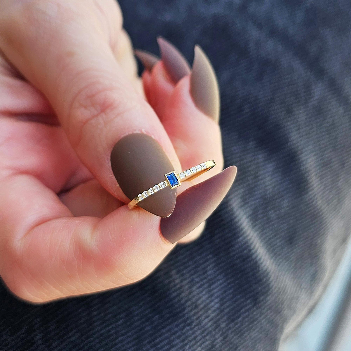 Gold blue-stone baguette ring worn on hand, close-up
