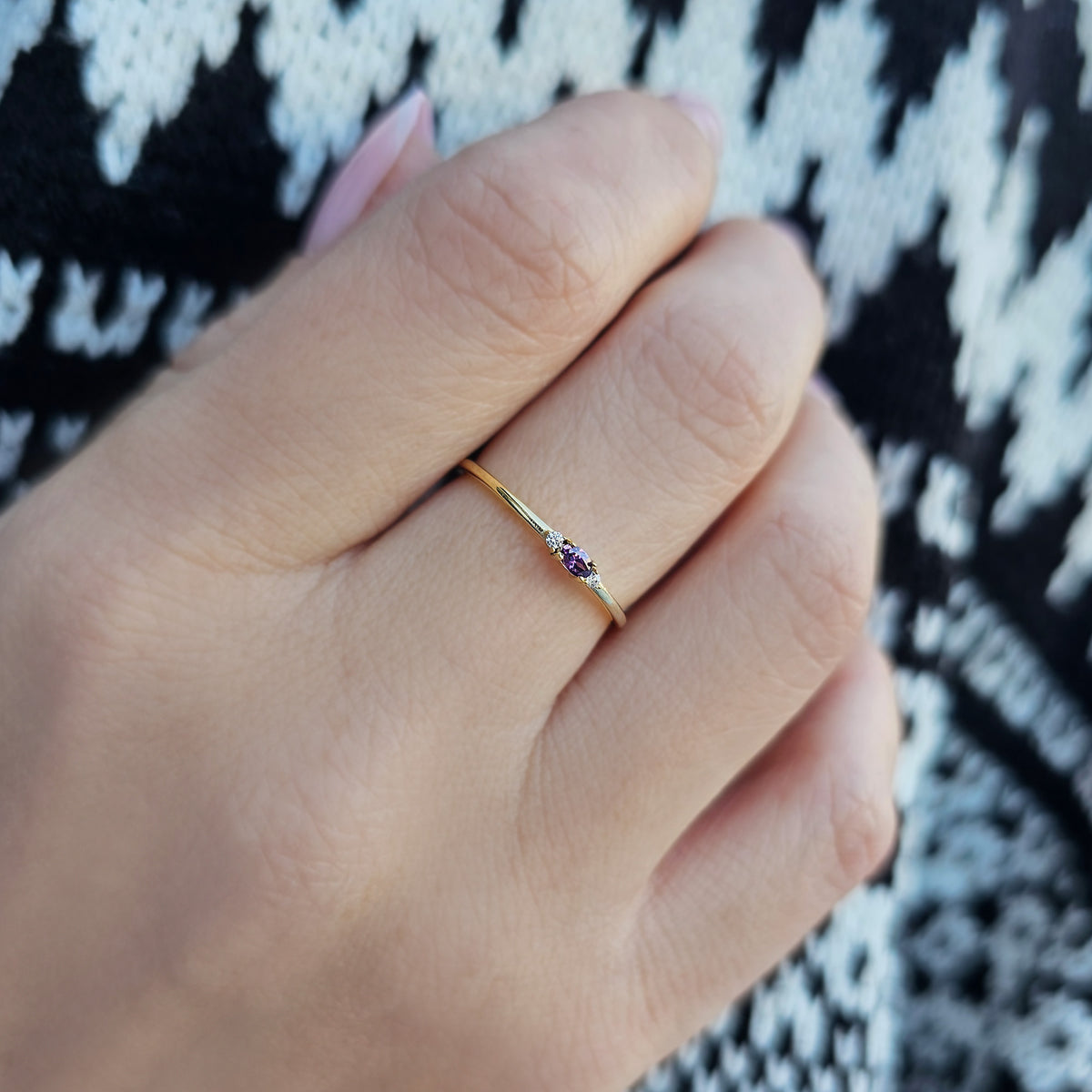 Gold purple-stone three-stone oval ring worn on hand, side view