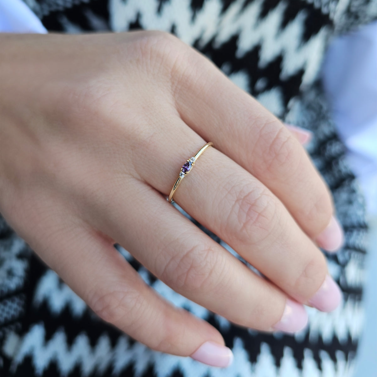 Gold purple-stone three-stone oval ring on raised hand