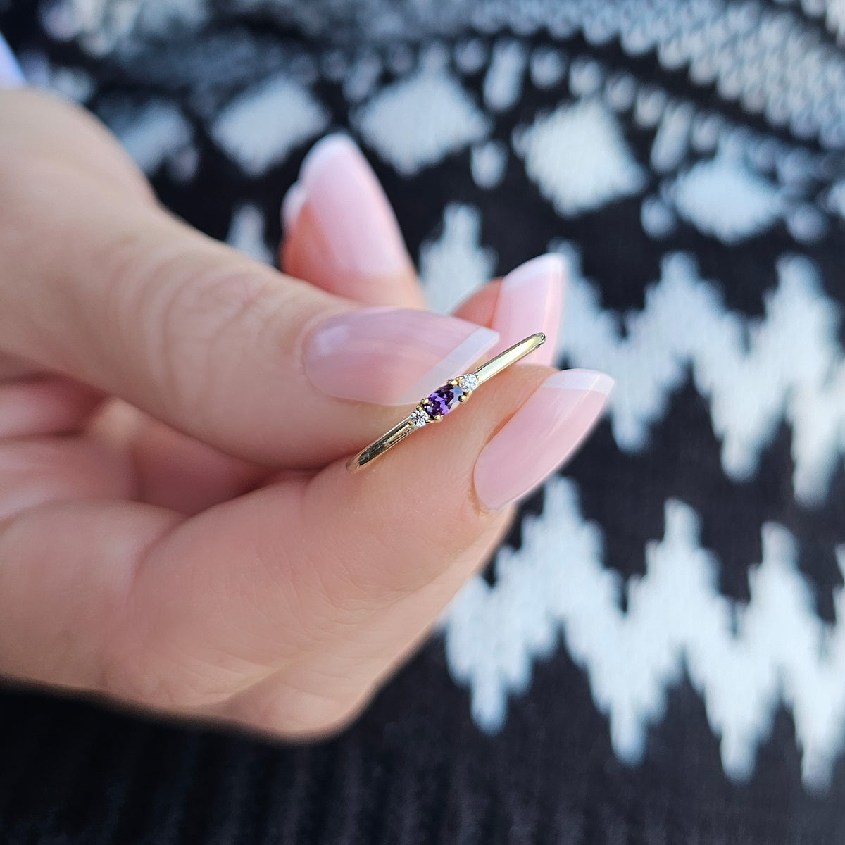 Gold purple-stone three-stone oval ring worn on hand, close-up