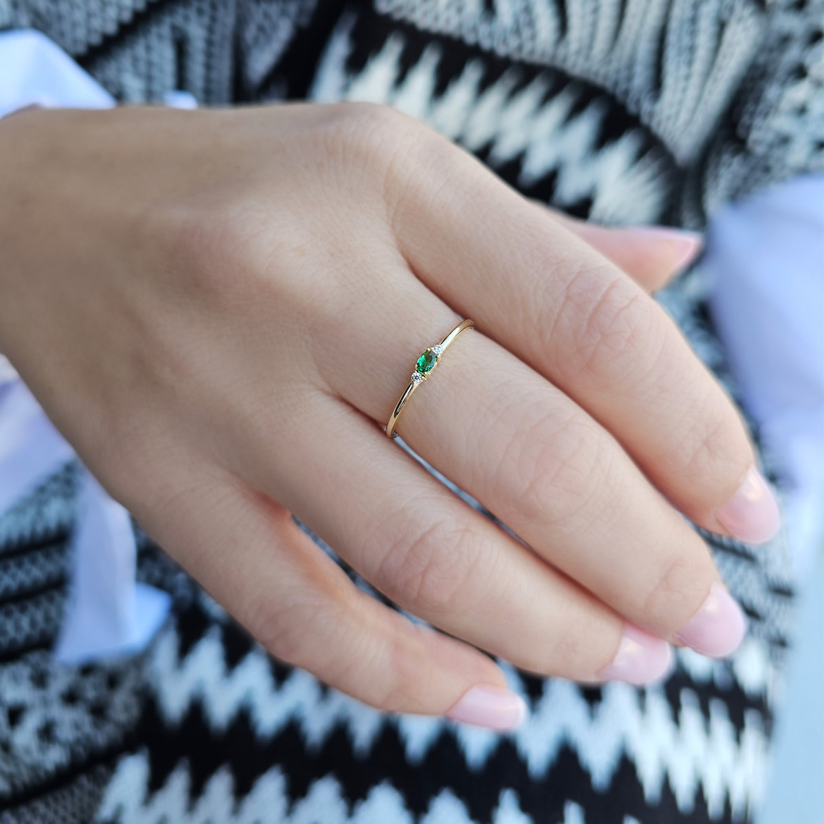 Gold green-stone three-stone oval ring worn on hand, close-up