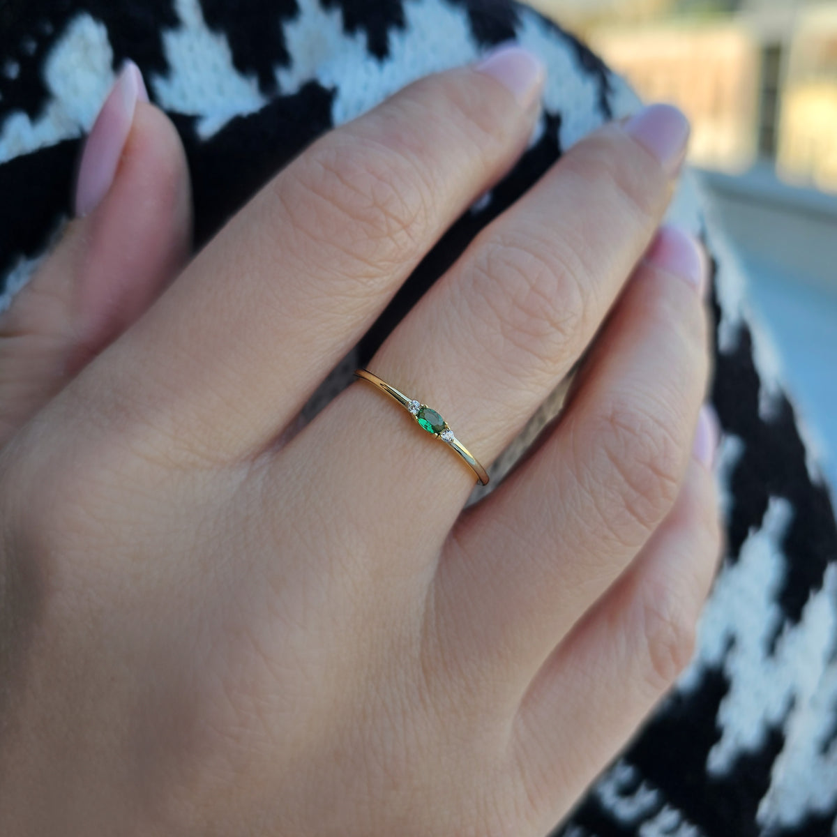Gold green-stone three-stone oval ring worn on hand, side view
