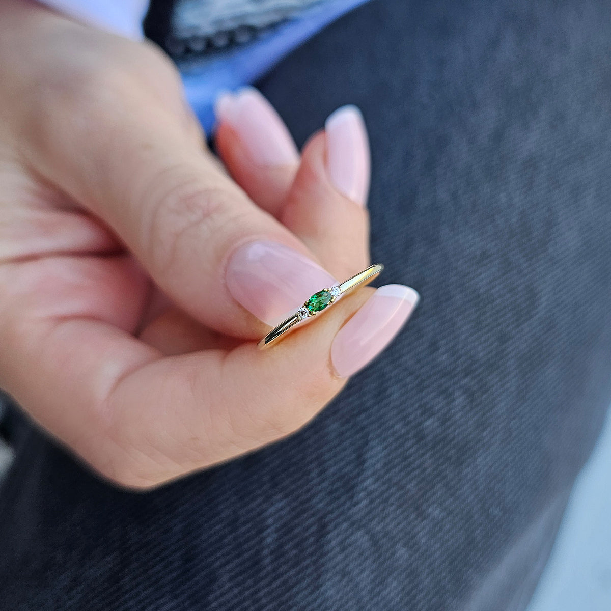 Gold green-stone three-stone oval ring on raised hand