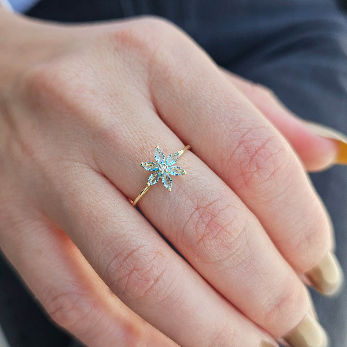 Gold aqua-blue-stone marquise flower ring worn on hand