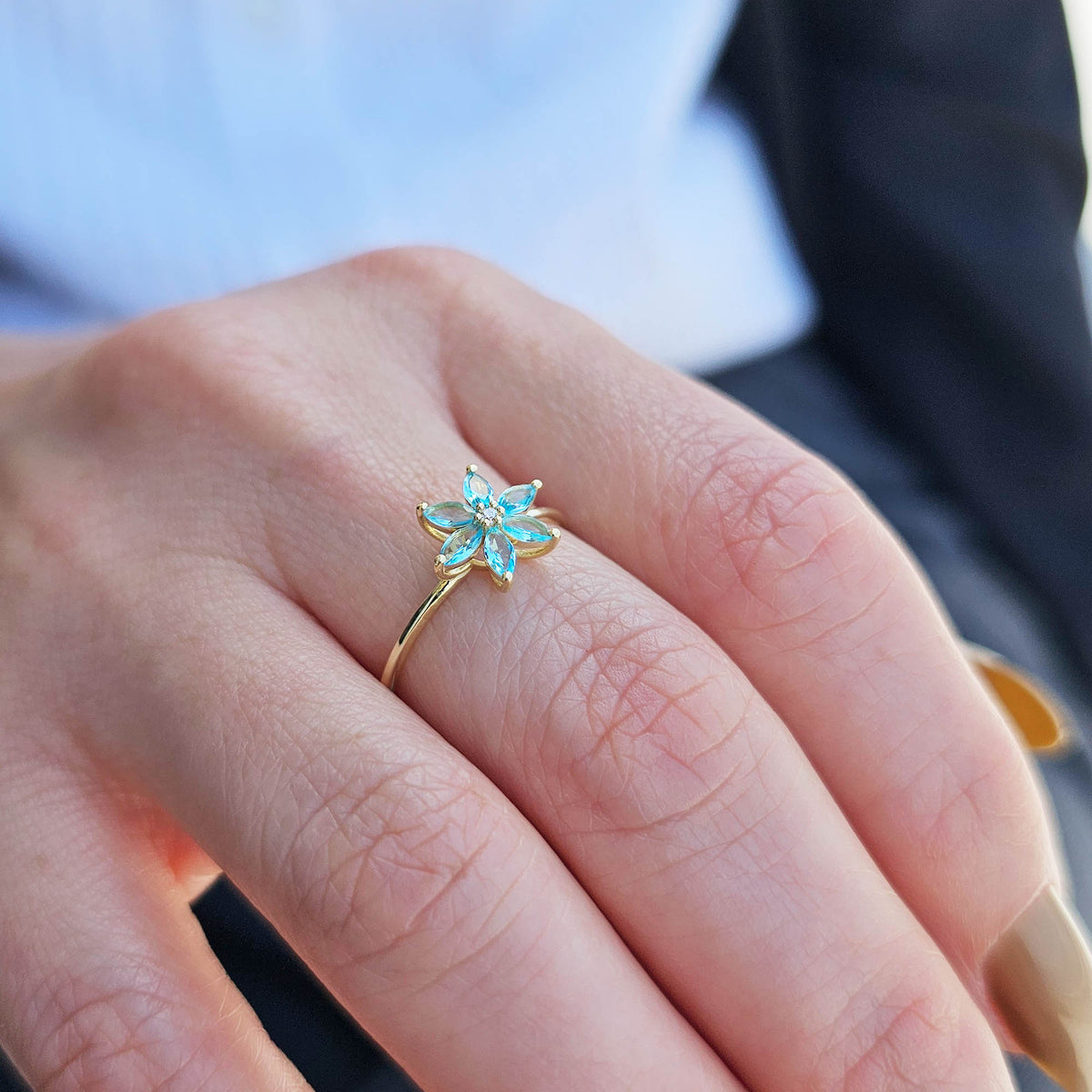 Gold aqua-blue-stone marquise flower ring worn on hand, side view