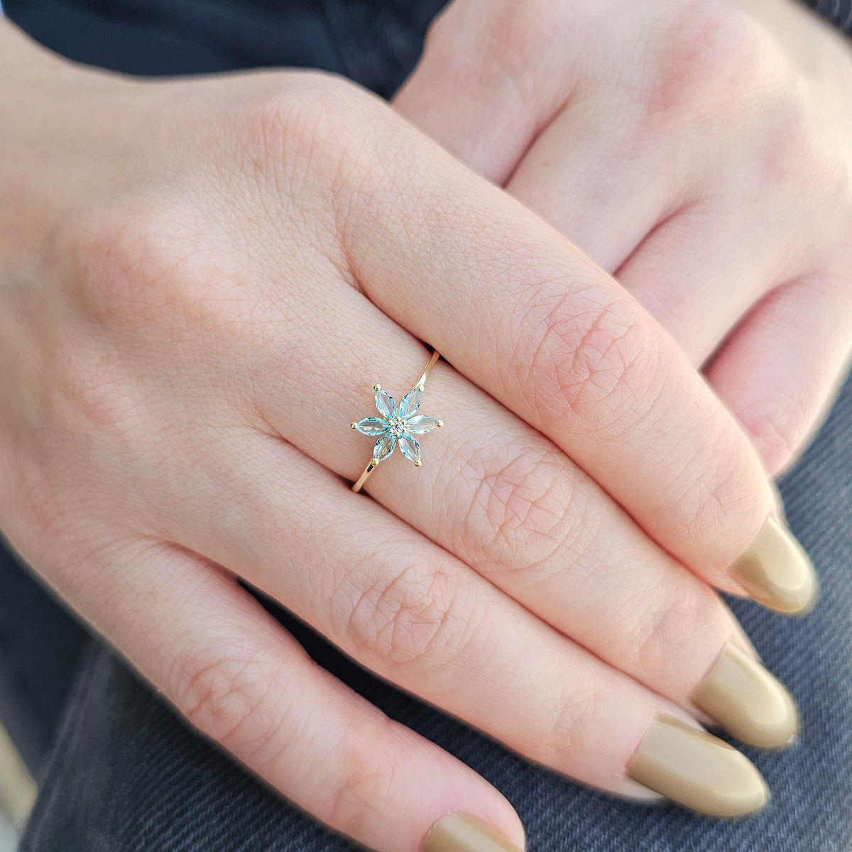 Gold aqua-blue-stone marquise flower ring on raised hand