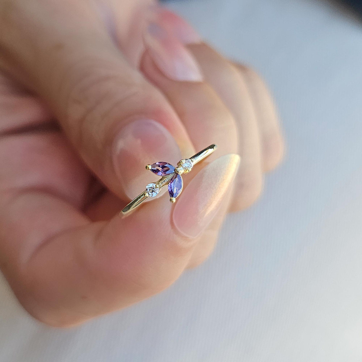 Gold purple-stone marquise leaf ring on raised hand
