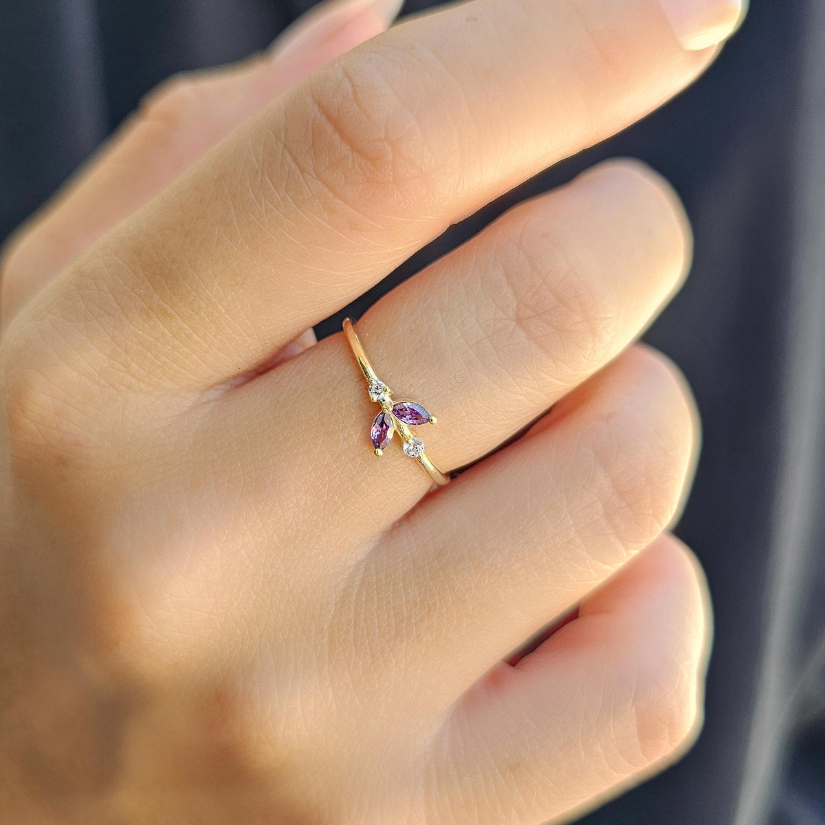 Gold purple-stone marquise leaf ring worn on hand, close-up