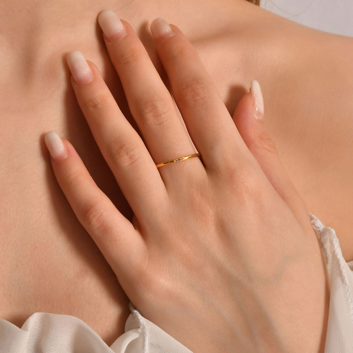 Gold single-diamond wedding ring worn on hand, side view