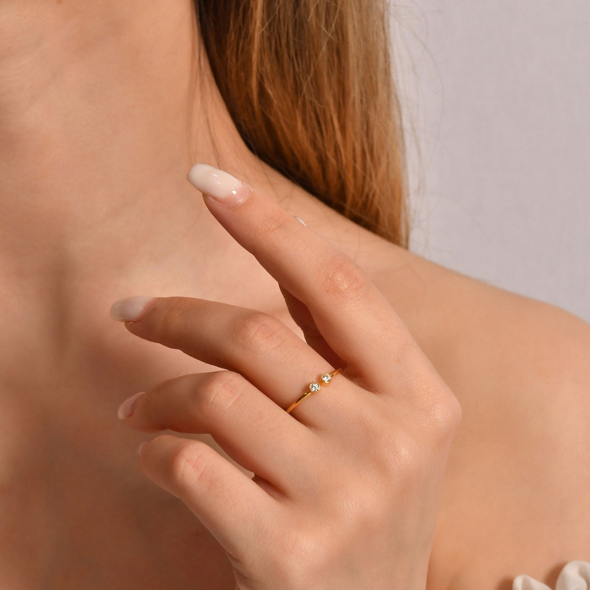 14K gold open two stone bezel diamond ring on raised hand
