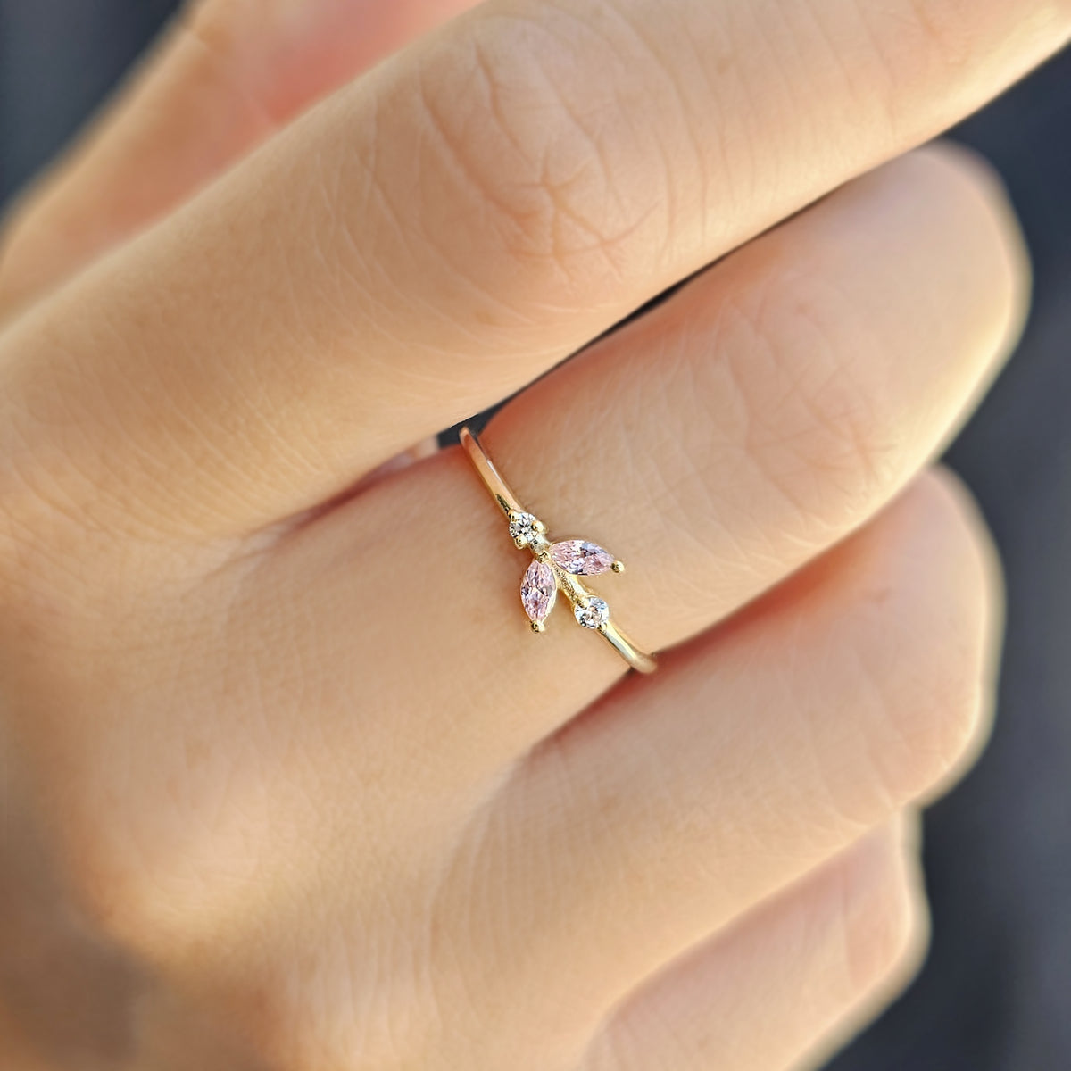 Gold pink-stone marquise leaf ring worn on hand, close-up