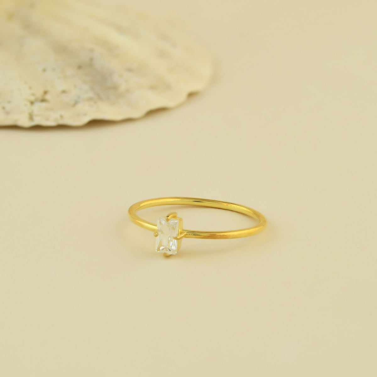 Gold white-stone baguette solitaire ring on raised hand