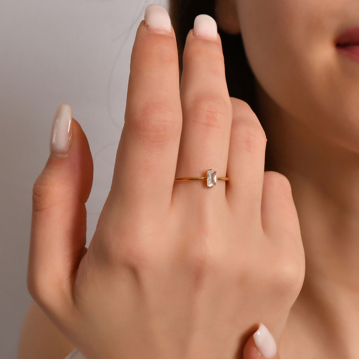 Gold white-stone baguette solitaire ring worn on hand