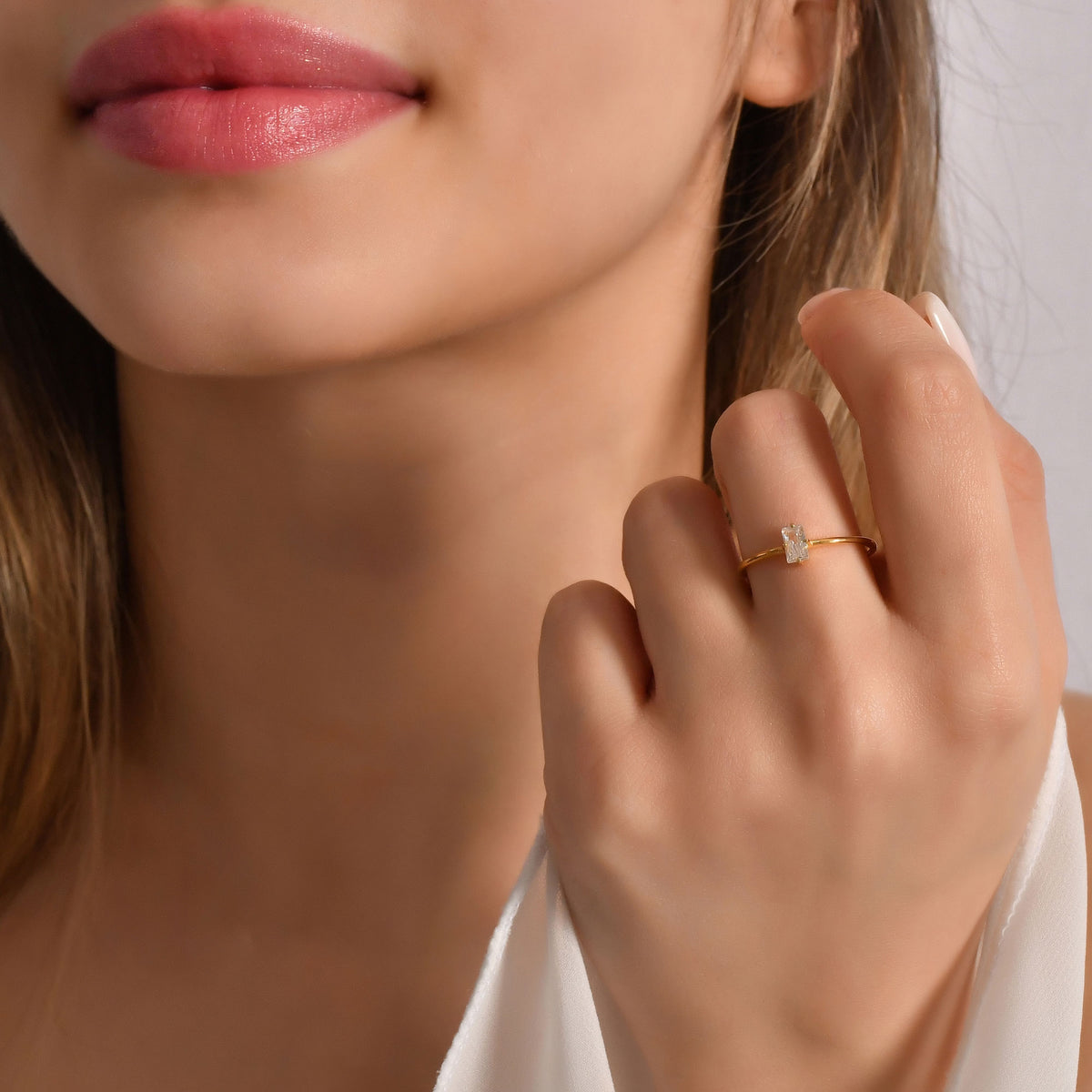 Gold white-stone baguette solitaire ring worn on hand, close-up