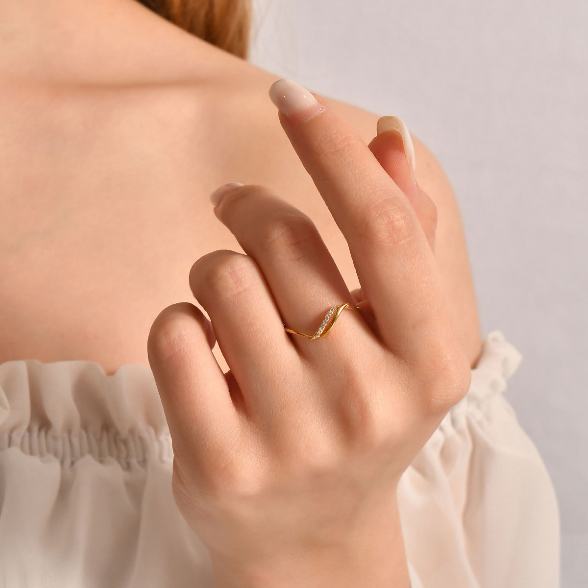 14K gold thin wave cubic zirconia ring on raised hand