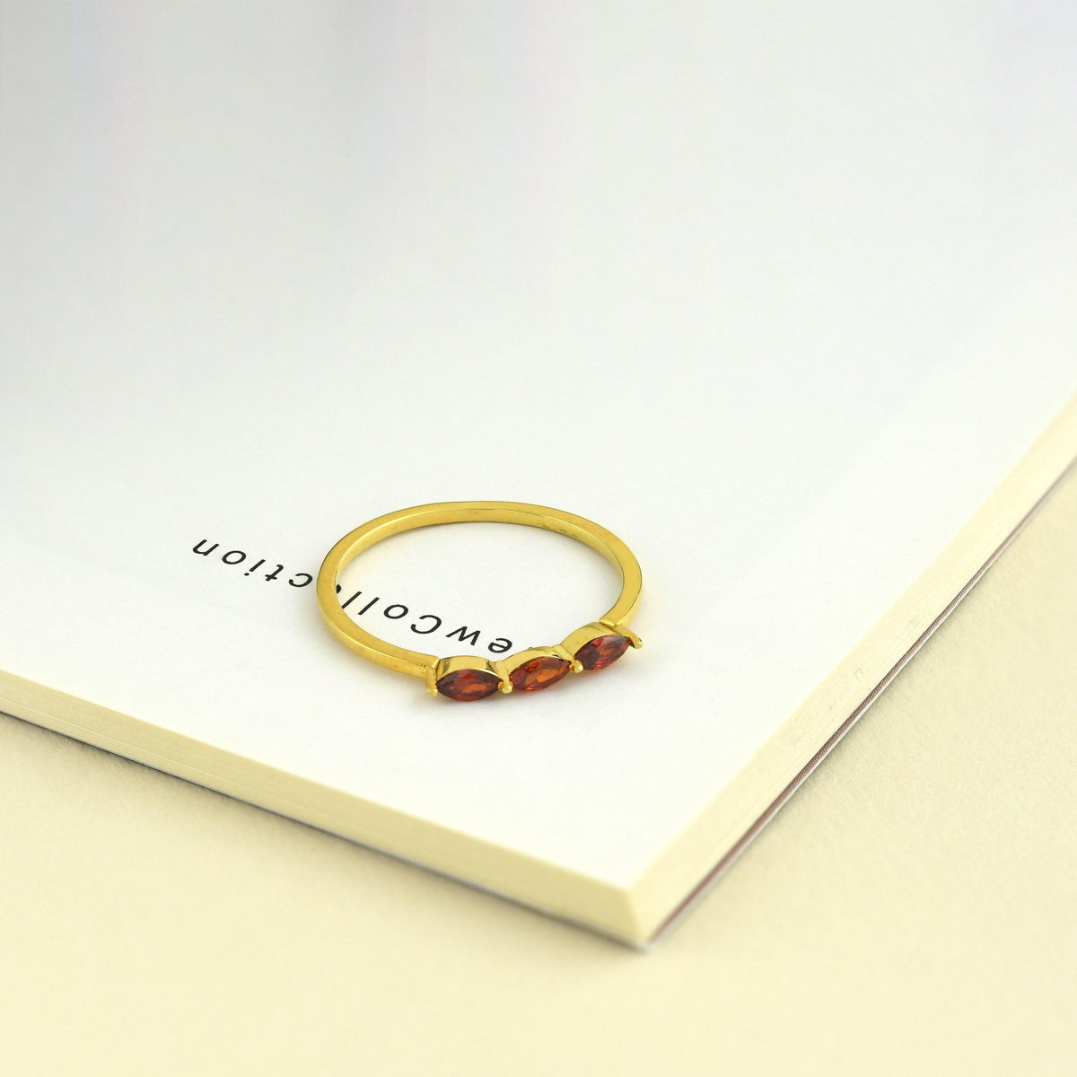 18K gold three stone marquise ring with orange-red marquise stones on display