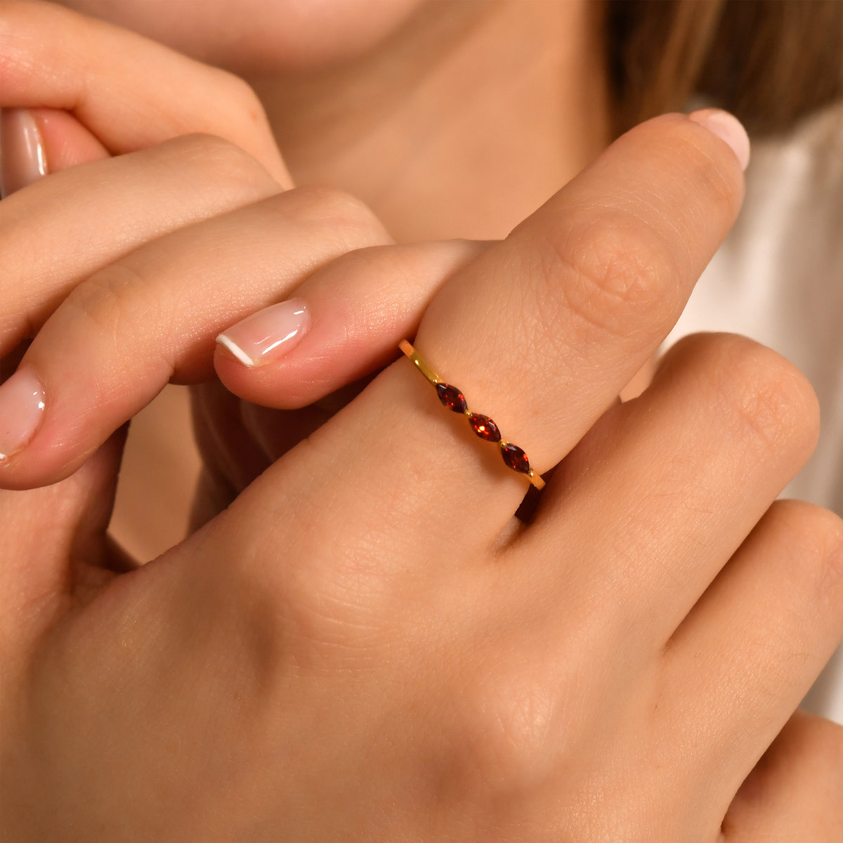 10K gold three stone marquise ring with orange-red marquise stones worn on hand