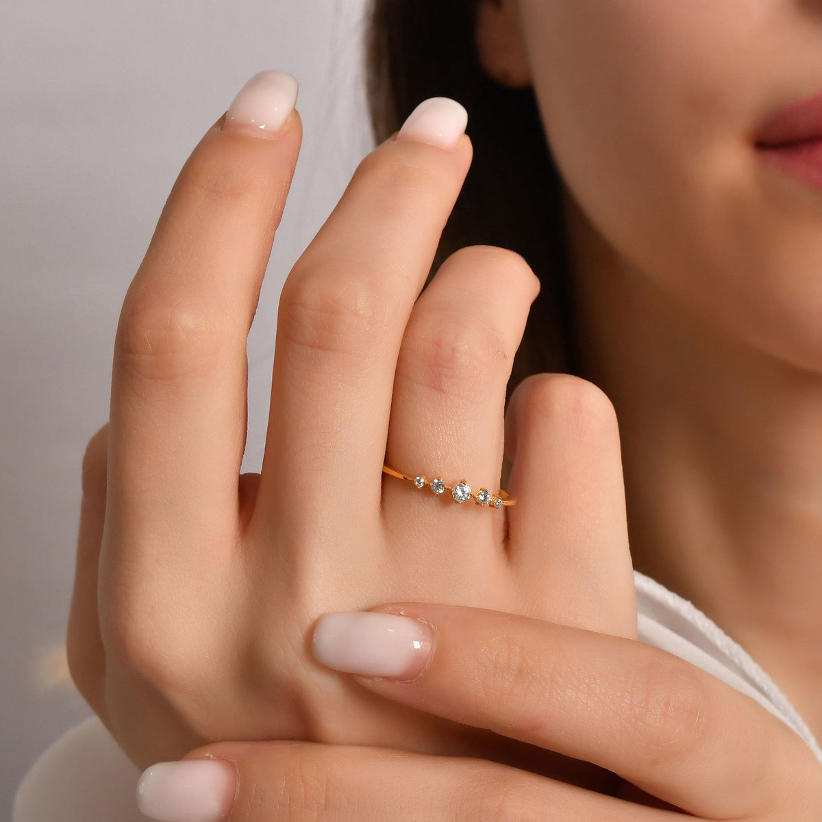 18K gold graduated five stone diamond ring on finger, close-up