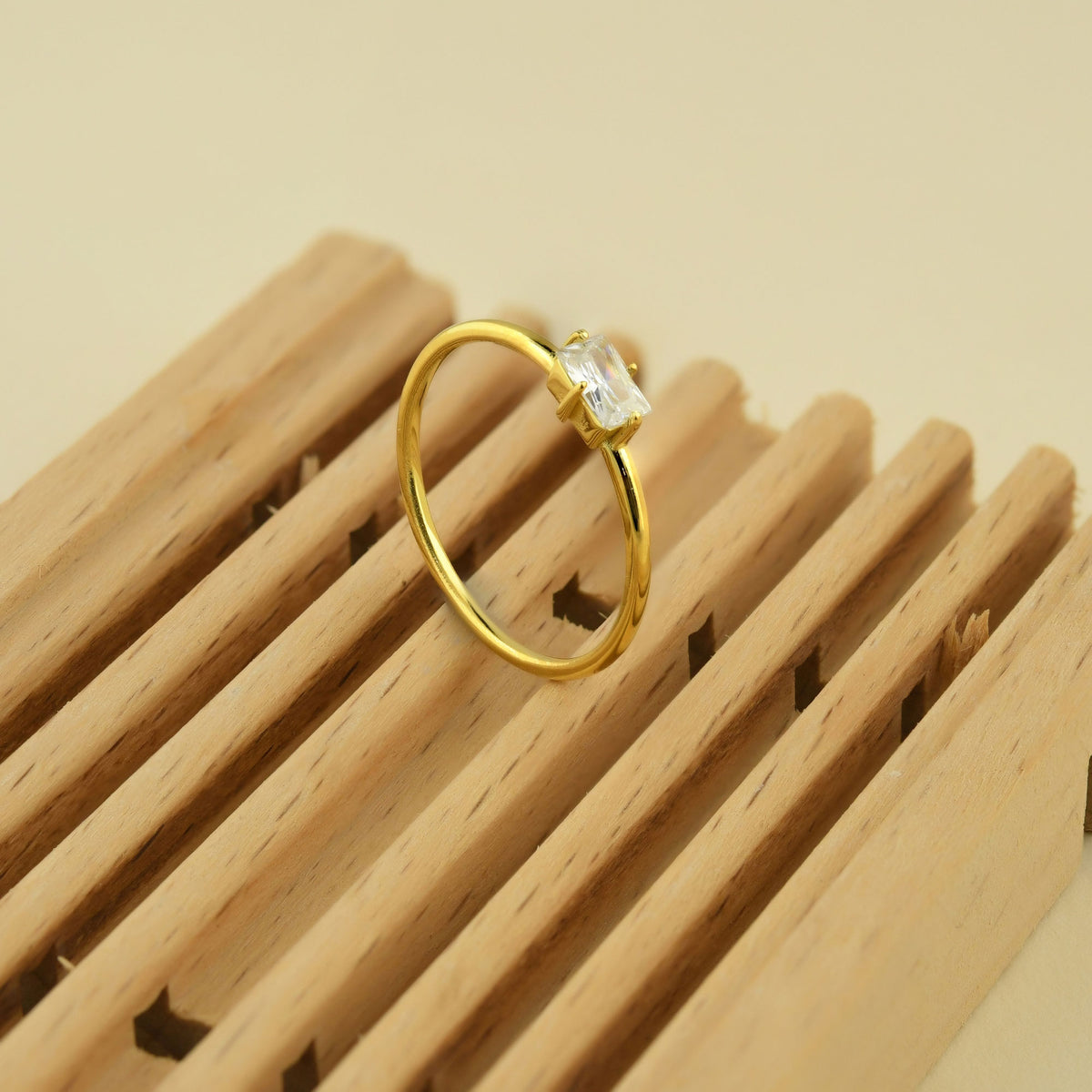 Gold white-stone baguette solitaire ring on raised hand