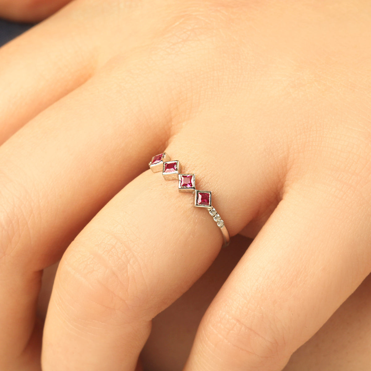 10K gold red stone four princess cubic zirconia ring on raised hand