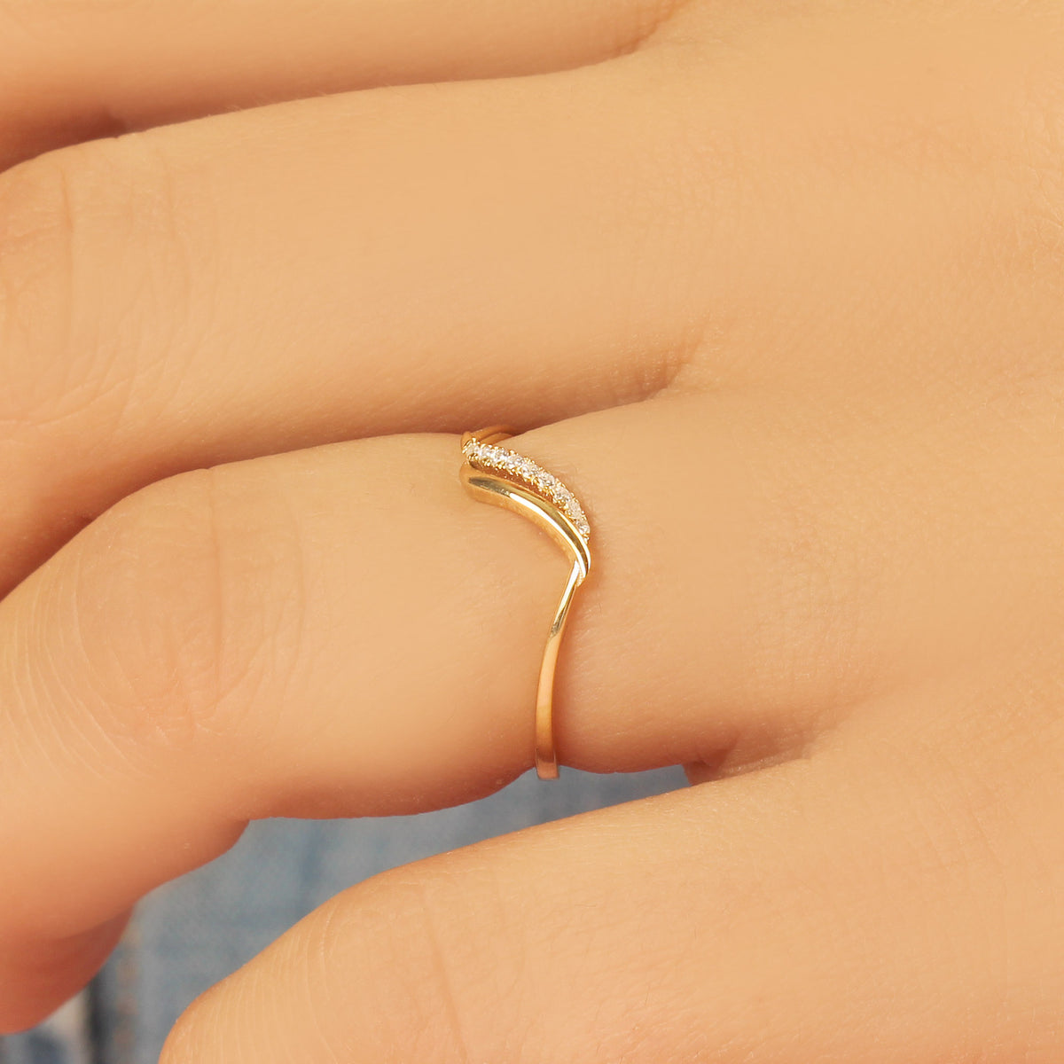 18K gold thin wave diamond ring worn on hand, close-up