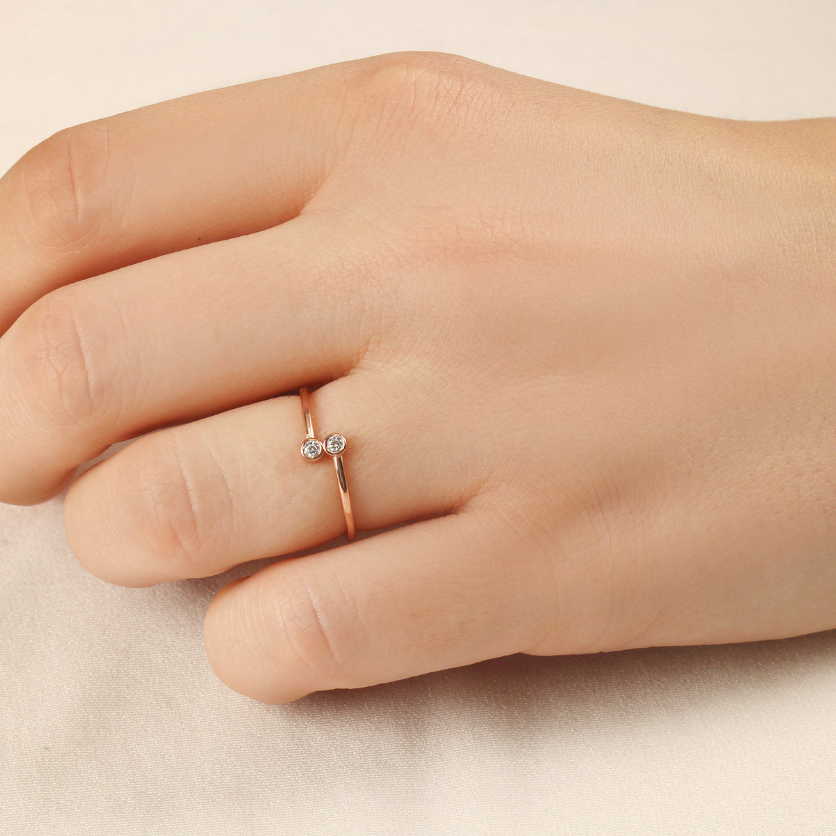 18K gold toi et moi bezel diamond ring worn on hand, side view