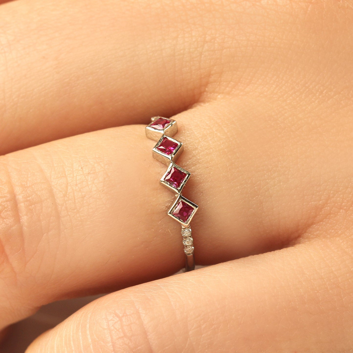 18K gold red stone four princess cubic zirconia ring on finger, close-up