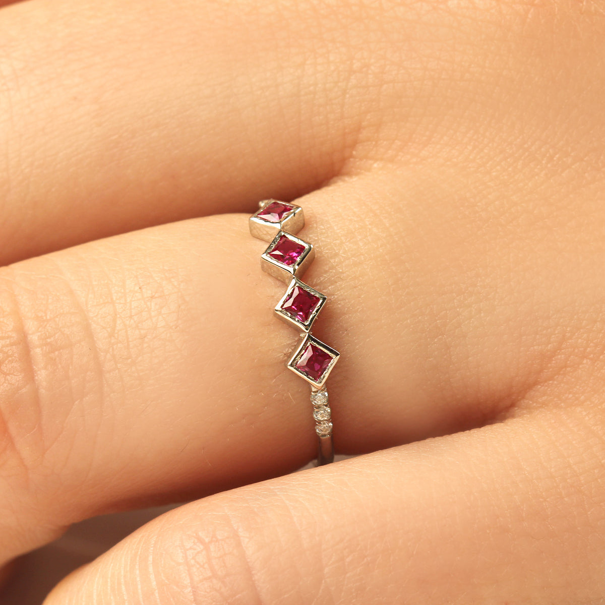 10K gold red stone four princess cubic zirconia ring on finger, close-up
