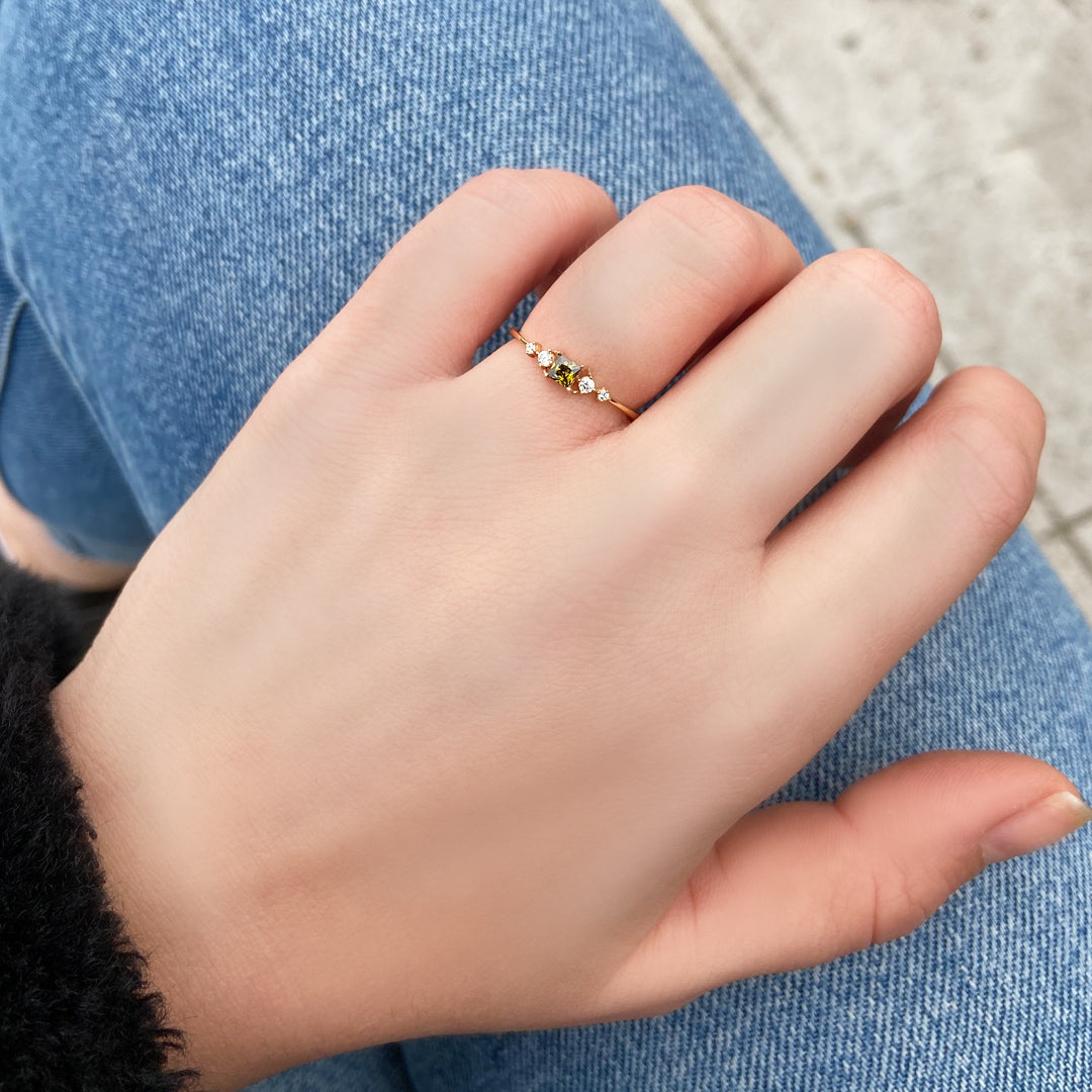 18K gold green-stone princess cubic zirconia ring on finger, close-up