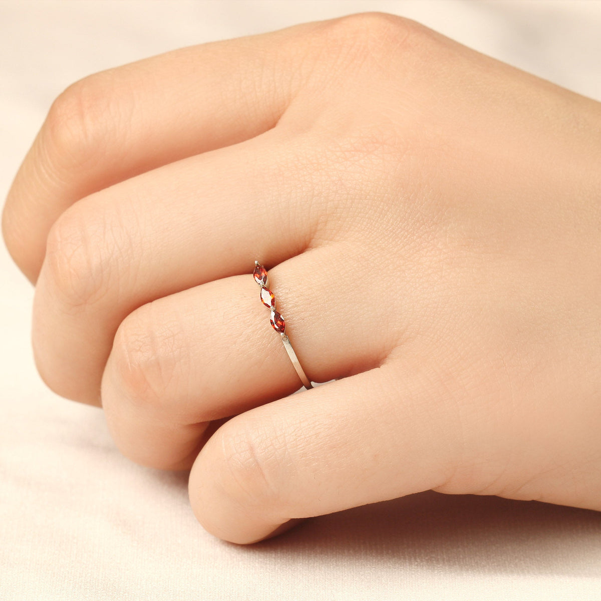 18K gold three stone marquise ring with orange-red marquise stones worn on hand, side view